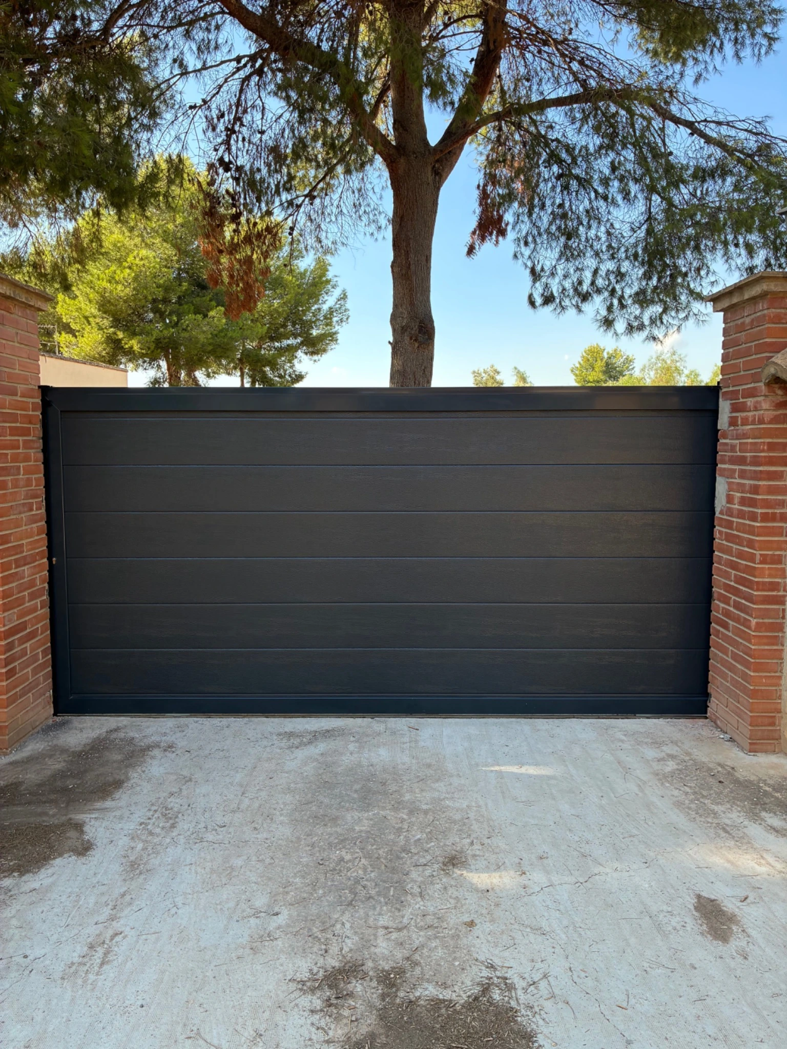 Resultado exterior: puerta corredera automática en acabado antracita texturado.
