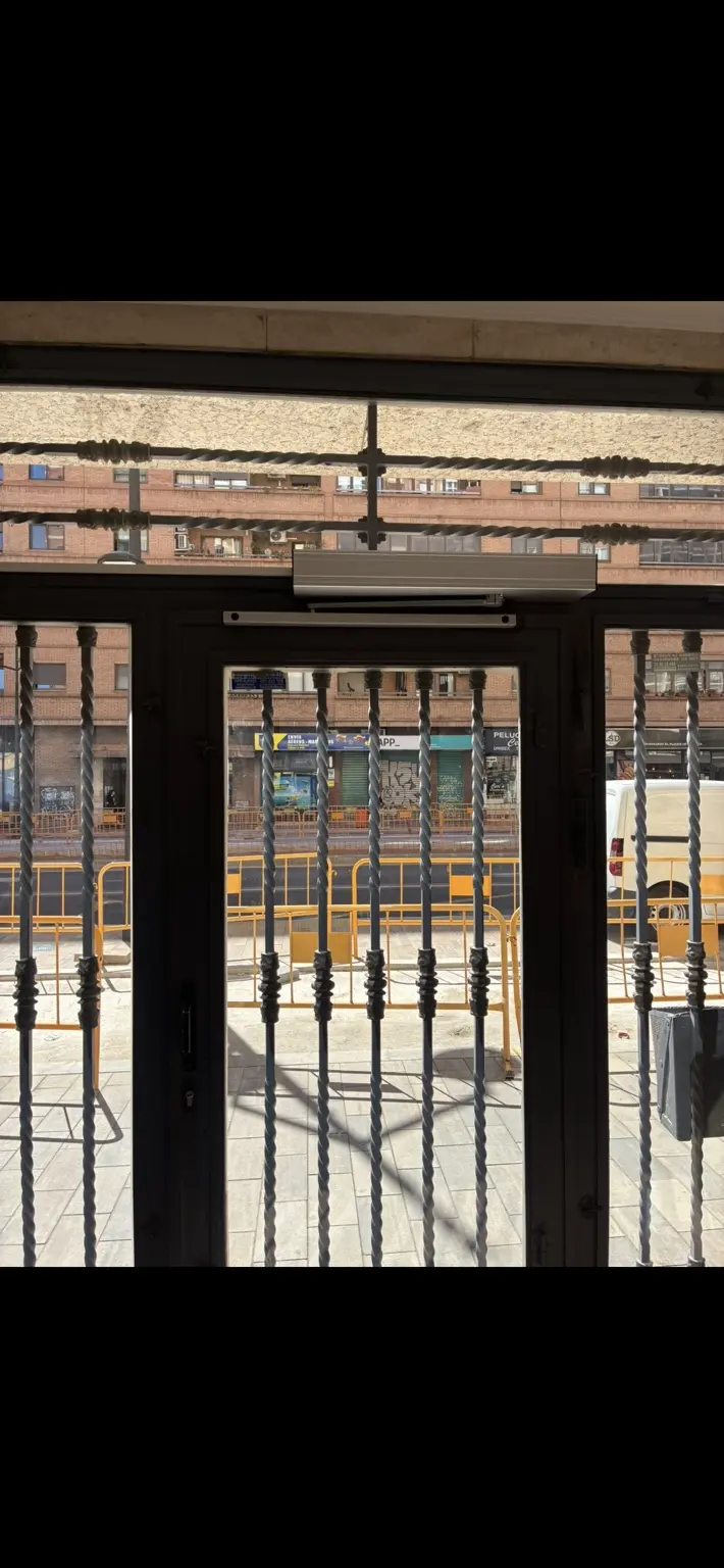 Operador automático instalado sobre la puerta peatonal del patio comunitario.